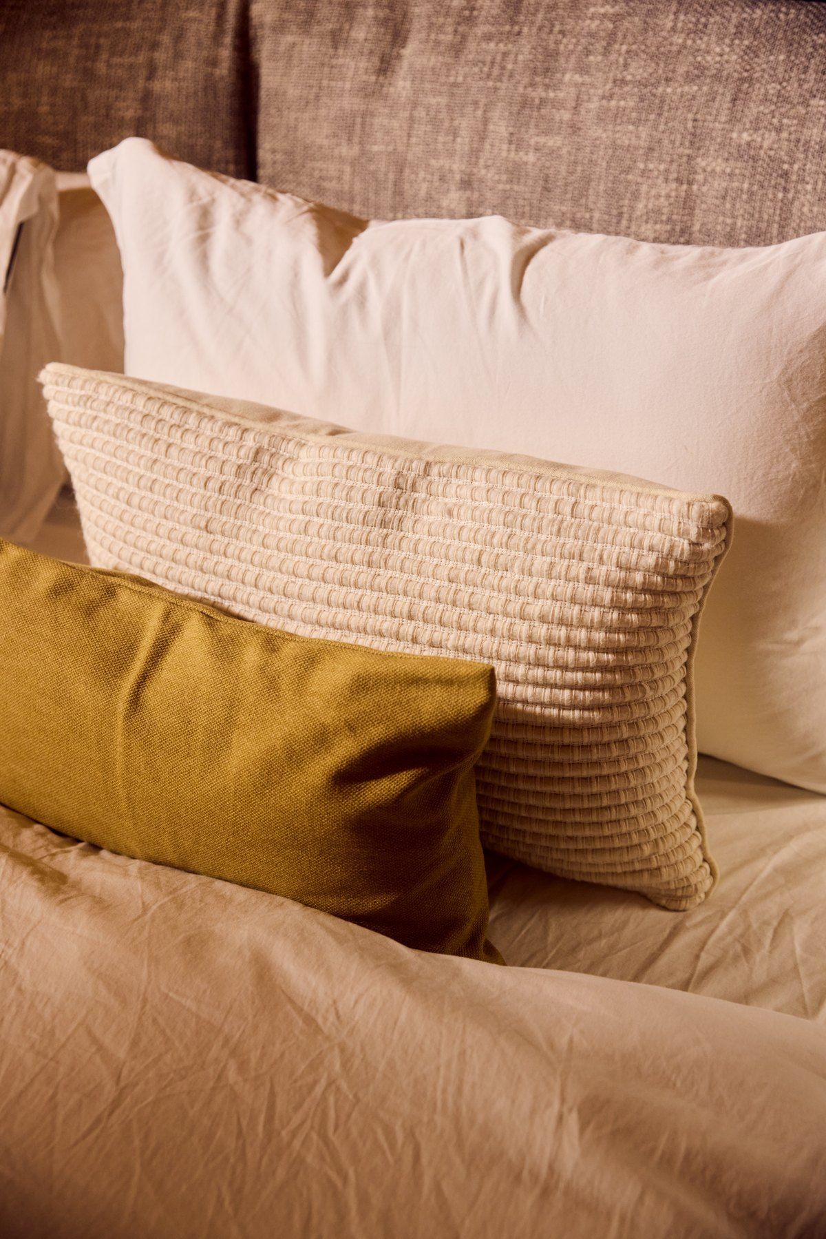 Bedding, an olive cushion and a linen headboard