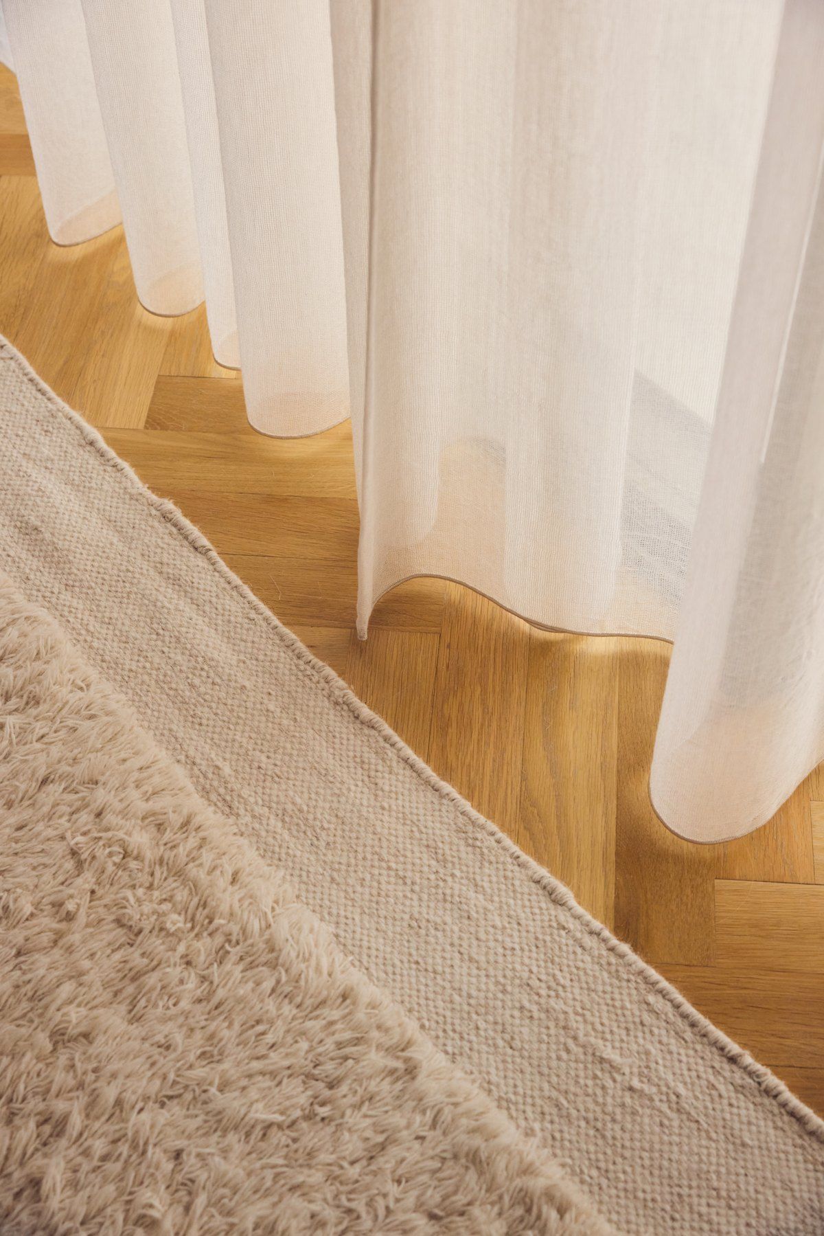 Sheer curtain meeting parquet at the foot of the stair