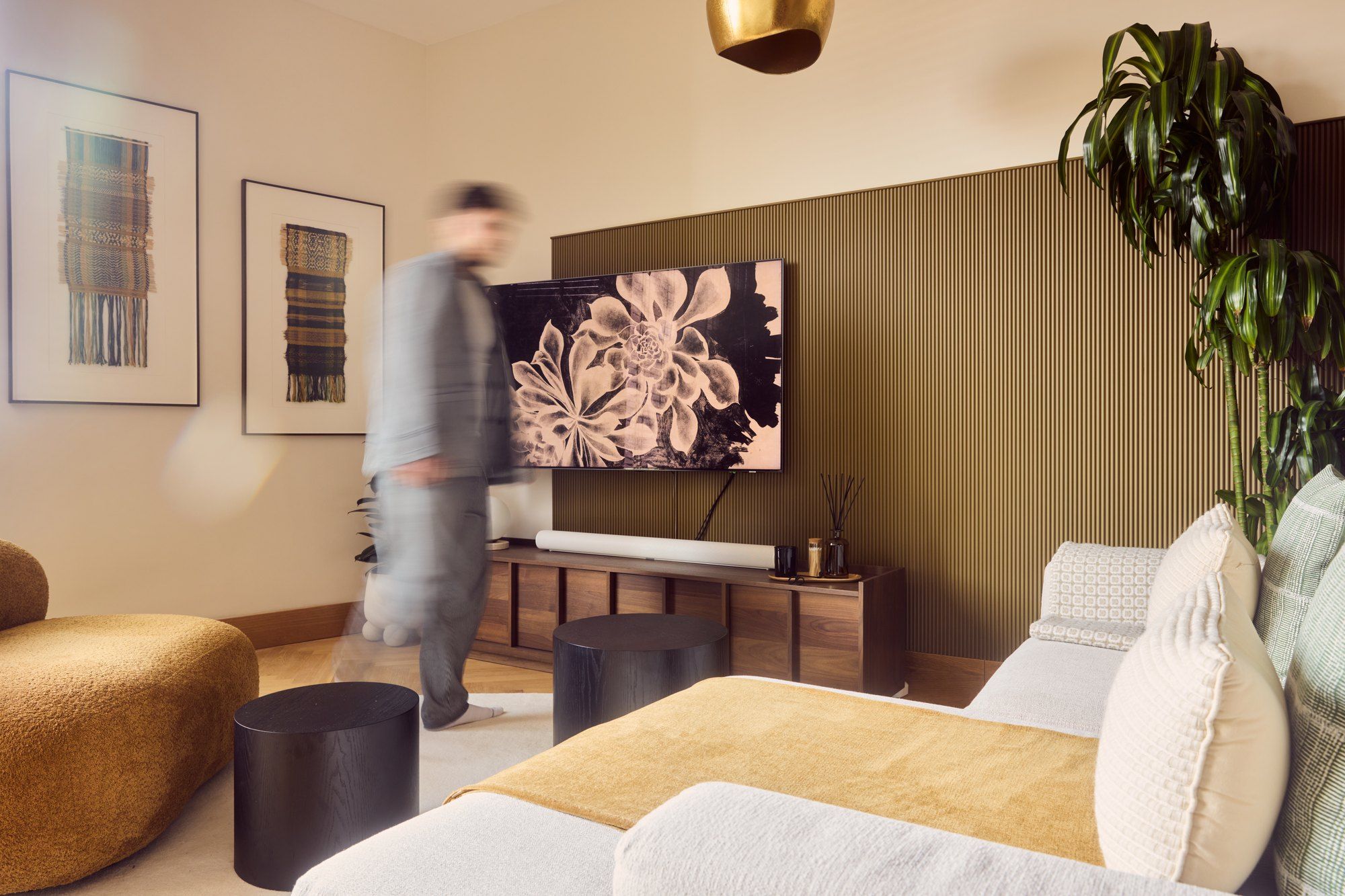 The living room, with fluted panelling, a brass pendant and Matt Smith-Wood walking through the frame