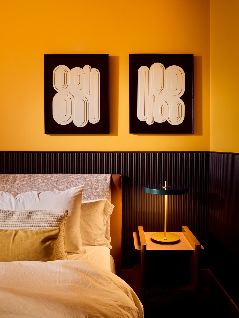Principal bedroom with ochre walls, fluted panelling and a brass lamp, Lisbon
