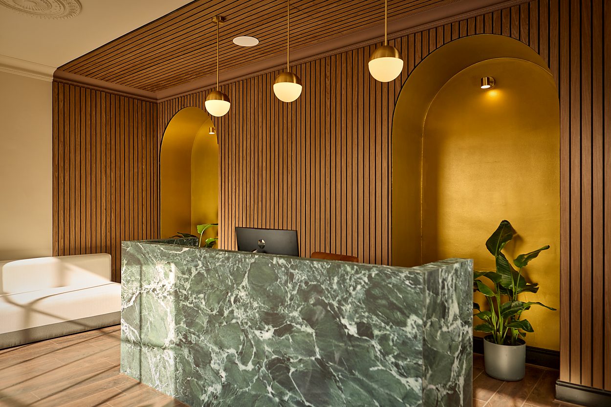The reception as built, the desk in pale green marble below ochre arched niches
