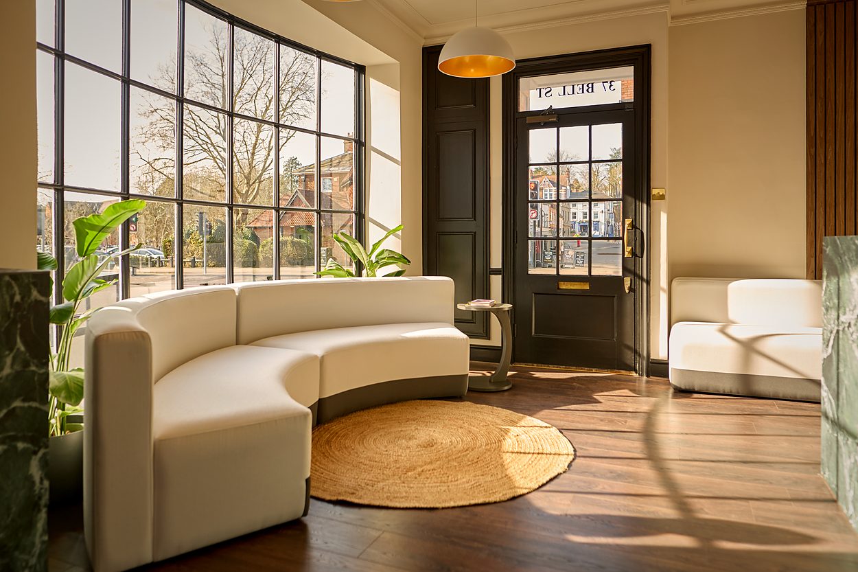 The same view as built, a curved cream sofa on a jute rug over plank flooring